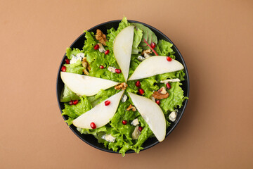 Delicious pear salad in bowl on beige background, top view