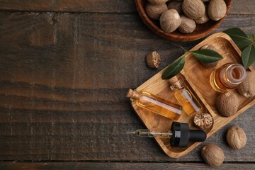 Nutmeg essential oil and nuts on wooden table, flat lay. Space for text