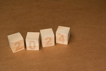 Wooden cube blocks with 2024 text on brown background. Start new year and business vision concept