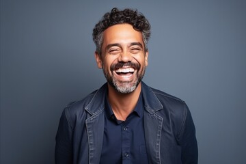 Portrait of a happy man laughing and looking at camera against grey background.