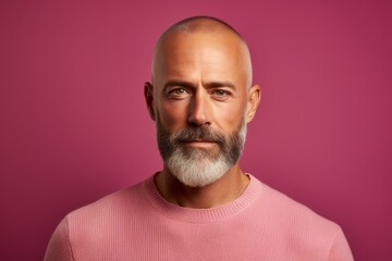 Obraz premium Portrait of a mature man with a beard on a pink background.