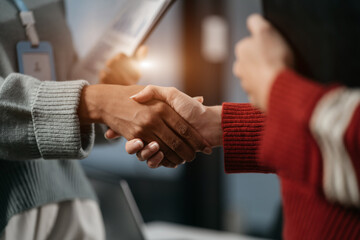 Business men and women shake hands confidently at an office meeting.