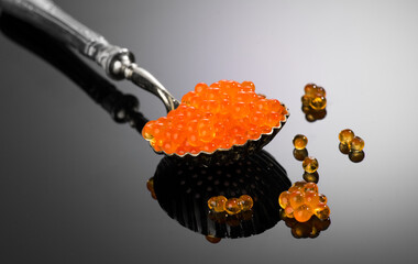 Red Caviar in a spoon over gray background. Close-up of salmon fish roe caviar. Delicatessen....
