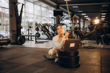 Portrait of a female personal trainer holding tablet and smiling at the camera in a gym.