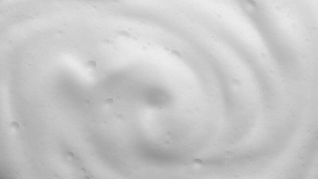 Foam texture backdrop on blue background. Liquid soap bubbles, Froth bubbles backdrop. Soap foam popping bubble rotating. Soap sud macro structure close-up. Clean, cleaning, washing, laundry 