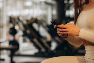 Fitness girl using her phone in the gym and listen to music