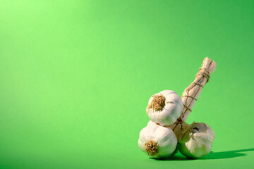 A short string of garlic against a seamless green background