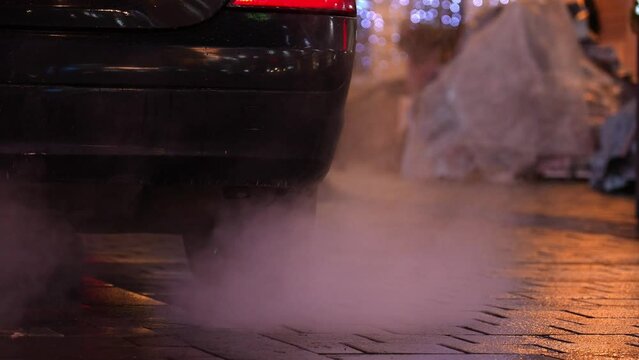 Close-up of car smoking exhaust pipe, car with gasoline engine. Warming up engine at idle speed in winter season. Blue exhaust smoke. Exhaust pipe of car, from which exhaust gases come out strongly