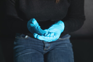 Caucasian woman wearing blue medical gloves.
