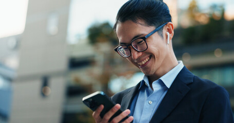 Phone, smile and Japanese businessman in the city reading company email on technology. Happy,...