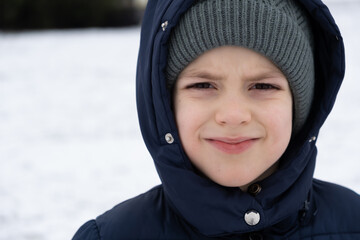 Six-year-old boy in warm winter clothes hat and jacket, close-up portrait.