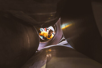 Hispanic male technician inspects stock material storage area steel coils large rolls metal sheets...
