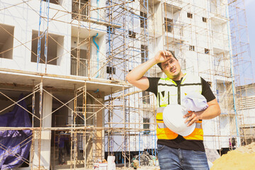 Foreman working outdoors condominium construction project exhausted from the hot weather and thirsty tired dizzy headache is dehydrated and wants to drink water suffer dehydration heatstroke.