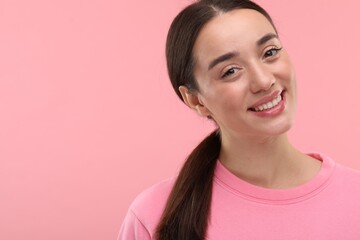 Beautiful woman with clean teeth smiling on pink background, space for text