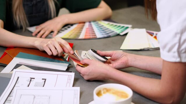 Close up hand choosing color from color sample swatch. The designer works with the customer and recommends the colors of decorative coatings.