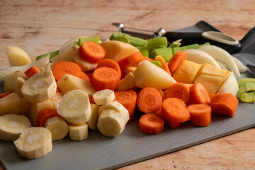 Chopped mixed raw vegetables consisting of parsnips, carrots, leek and sweet potatoes on a chapping...