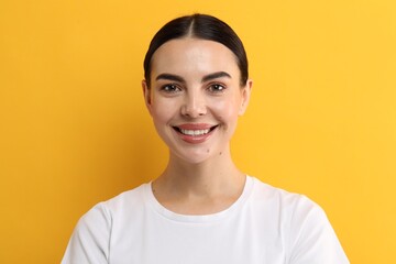 Beautiful woman with clean teeth smiling on yellow background