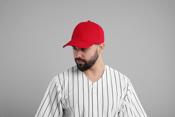 Man in stylish red baseball cap on light grey background