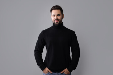 Happy man in stylish black sweater on grey background