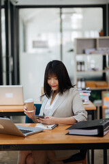 Successful Asian Businesswoman Analyzing Finance on Tablet and Laptop at modern Office Desk tax, report, accounting, statistics in office.