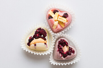 chocolate sweets in the form of a heart with fruits and nuts on a colored background. top view with space for text, holiday concept