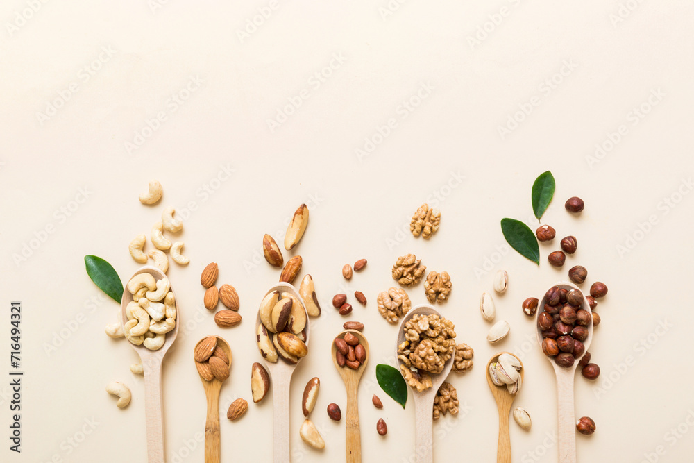 Wall mural mixed nuts in white wooden spoon. Mix of various nuts on colored background. pistachios, cashews, walnuts, hazelnuts, peanuts and brazil nuts - Wall murals