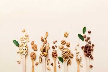 mixed nuts in white wooden spoon. Mix of various nuts on colored background. pistachios, cashews,...