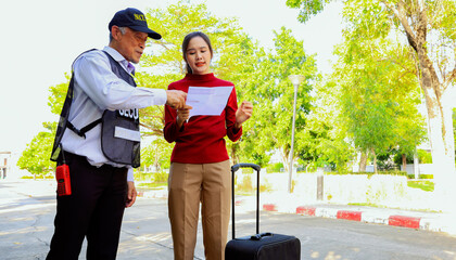 Travel of beautiful young woman with suitcase holding friend's address paper asked help senior male security guard in the village ask directions within the village but still couldn't find the house.