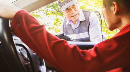 Asian woman driving car asks travel assistance and asks the senior male security guard standing provide friendly and polite service receives assistance in solving immediate problems efficiently.