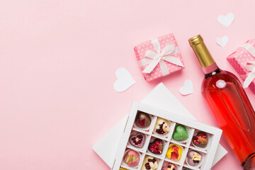 Naklejka na ściany i meble Bottle of red wine on colored background for Valentine Day with gift and chocolate. Heart shaped with gift box of chocolates top view with copy space