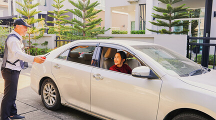 Senior security guards take care female residents with friendliness facilitating parking on the sidewalk providing friendly service with smile to the female residents driving carefully for safety.