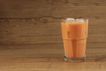 A Glass of Ice Thai Milk Tea on Wooden Table