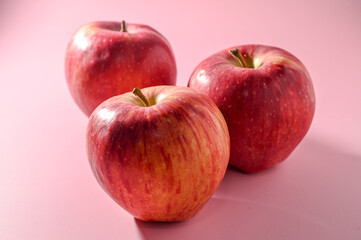 three red apples on a pink background 1