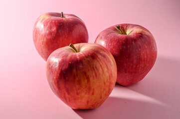 three red apples on a pink background 2