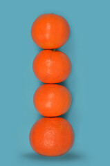 Stack of tangerines, mandarines 
tower (four mandarines) on a blue background. 