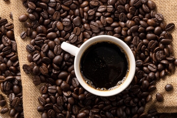 cup of coffee with beans on jute background
