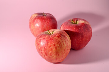 three red apples on a pink background 3