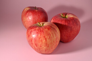 three red apples on a pink background 4
