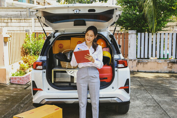 Beautiful asian businesswoman with successful business, preparing to move moving luggage in trunk...