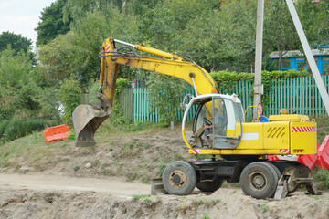 An excavator and other heavy construction equipment are working on the construction site. Construction of a new bridge across the river. Road works, laying of a new road.