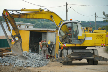 An excavator and other heavy construction equipment are working on the construction site. Construction of a new bridge across the river. Road works, laying of a new road.