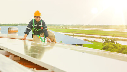 Asian male electrician engineer inspects installation of solar panels on metal roof in industrial...