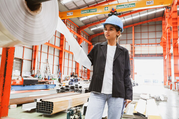Female inspection engineer inspects the quality of plastic rolls, galvanized sheets, metal sheets in an industrial factory with confidence, trusting the quality of the materials during production.