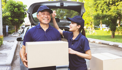 Delivery work home delivery service business : Retired senior male employee and female delivery driver stand together holding boxes waiting with smiles on their faces customers pick up their orders.