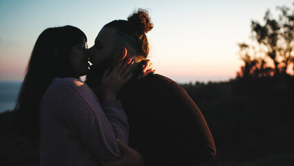 Young engaged couple kissing at sunset in valentines day