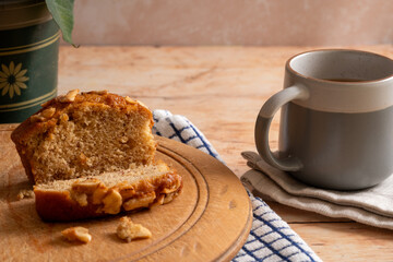 Banana bread sliced on a wooden chopping board and a cup of tea. Concept of rest and refreshment.
