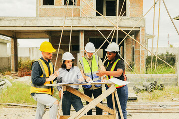 Meeting team multi-ethnic male and female architects construction engineers and male safety officers plans work and supervises workers to follow regulations within the housing construction project.