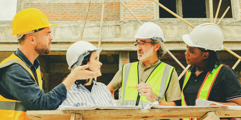Meeting team multi-ethnic male and female architects construction engineers and male safety officers plans work and supervises workers to follow regulations within the housing construction project.