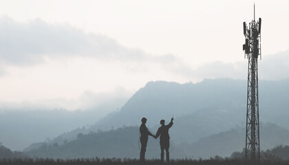 Silhouette team electricians architects two engineers holding hands successful installation of tall telecommunication towers in highland countryside communication expansion enhancement 5G technology. © ฺฺฺBoonterm