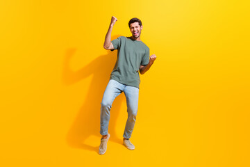 Full length photo of charming lucky man dressed khaki t-shirt shouting yes rising fists isolated yellow color background